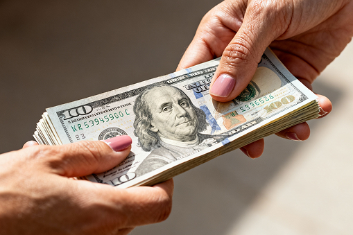 someone being handed US dollars